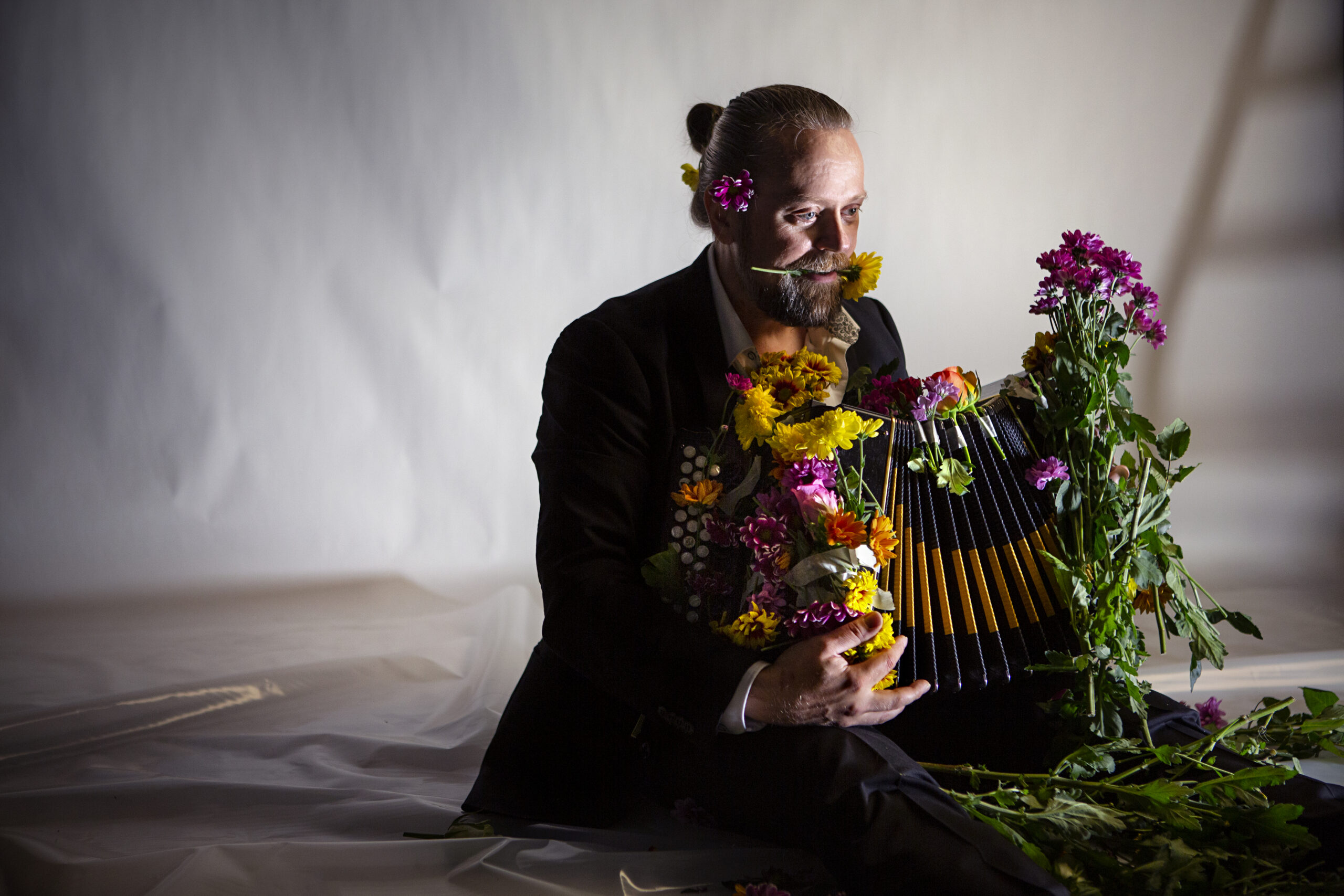 Kuvassa Antti Paalanen istuu haitari sylissään ja haitarin ympärillä on kukkia.