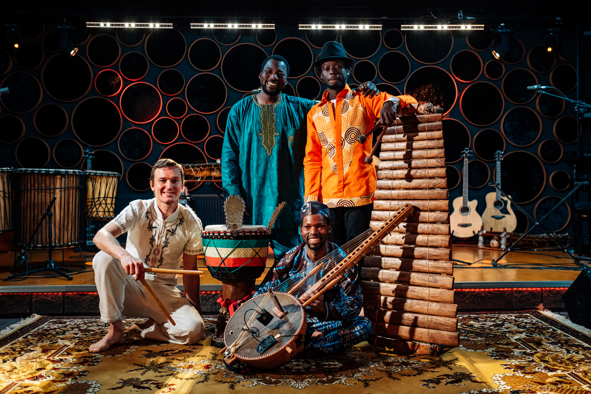 Kuvassa neljä muusikkoa yhdessä afrikkalaisten puusoittimien keskellä.